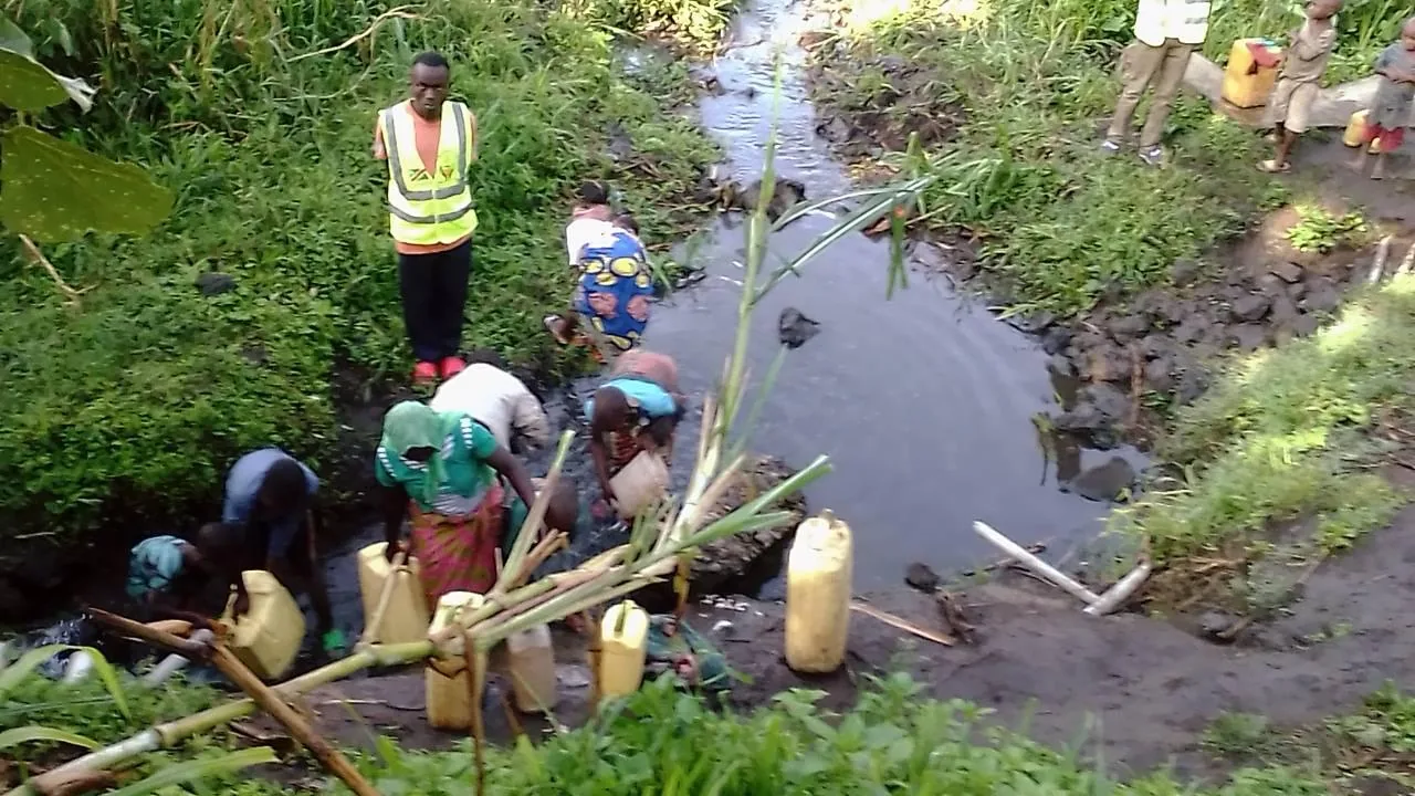 A PALPER volunteer helps families collect water safely