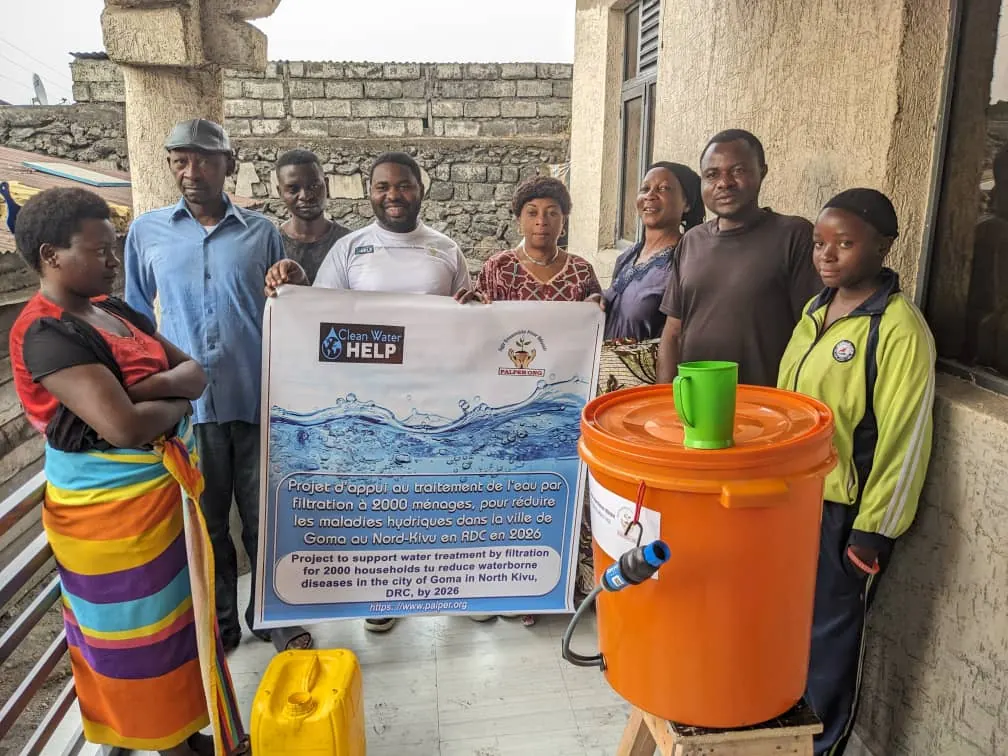 PALPER staff and a Goma family beside a newly installed orange bucket filter on a balcony