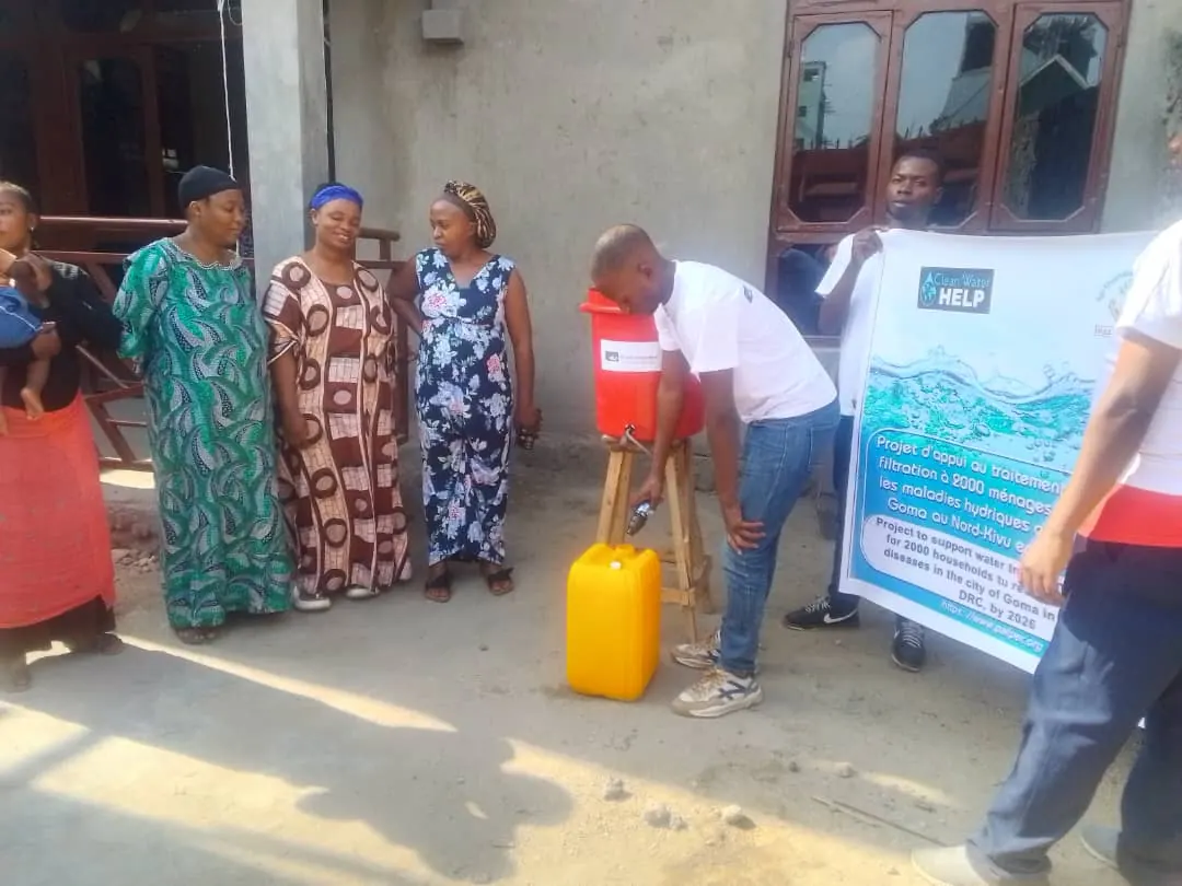 A PALPER team member demonstrates a bucket filter on a Goma street as neighbors watch
