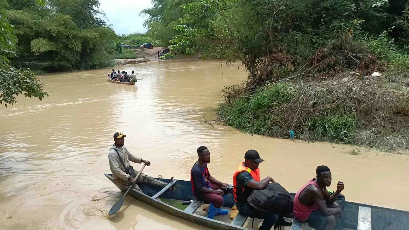 Dugout canoes ferry people across a polluted river