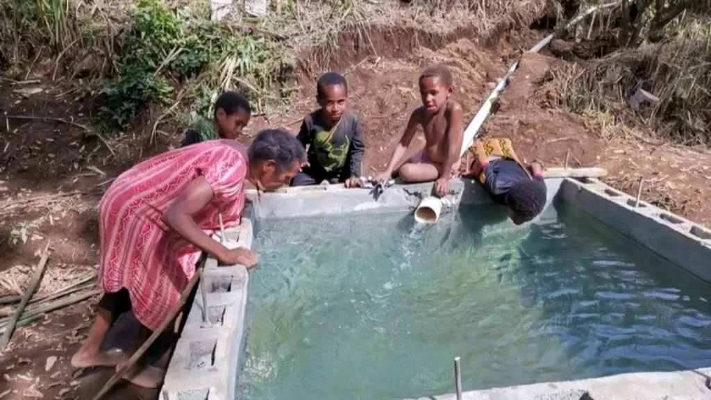 Villagers build a concrete water-catchment tank