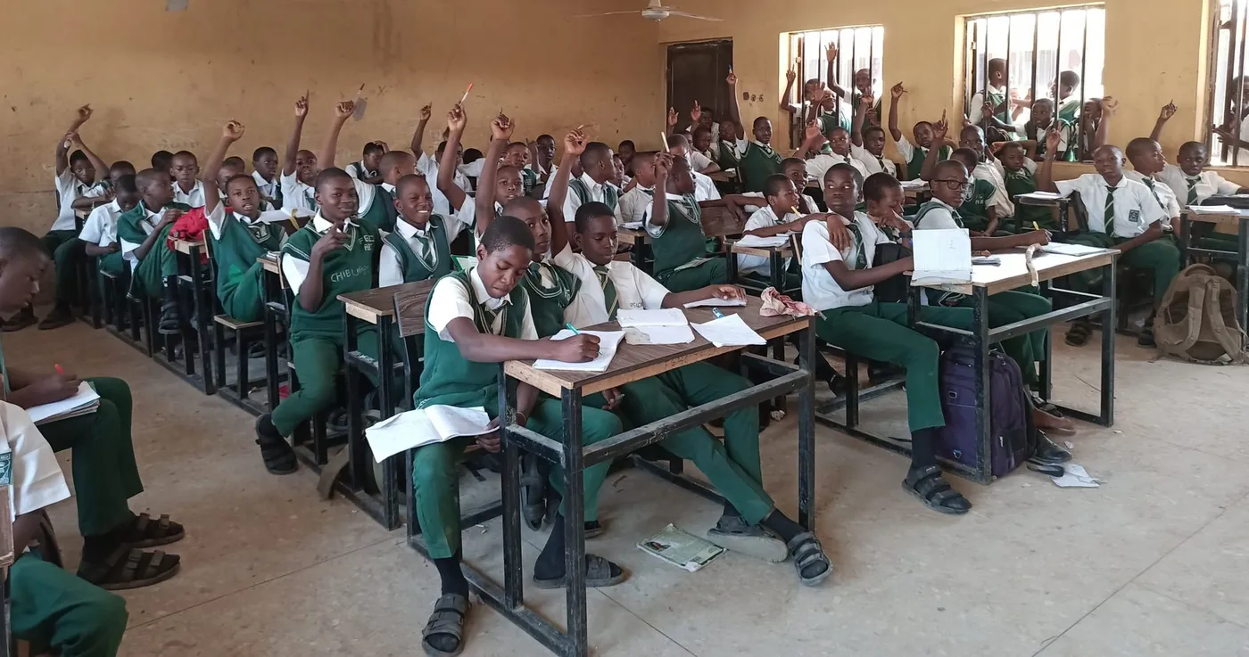 Students raising their hands eagerly in a bright classroom in North Kivu, DR Congo
